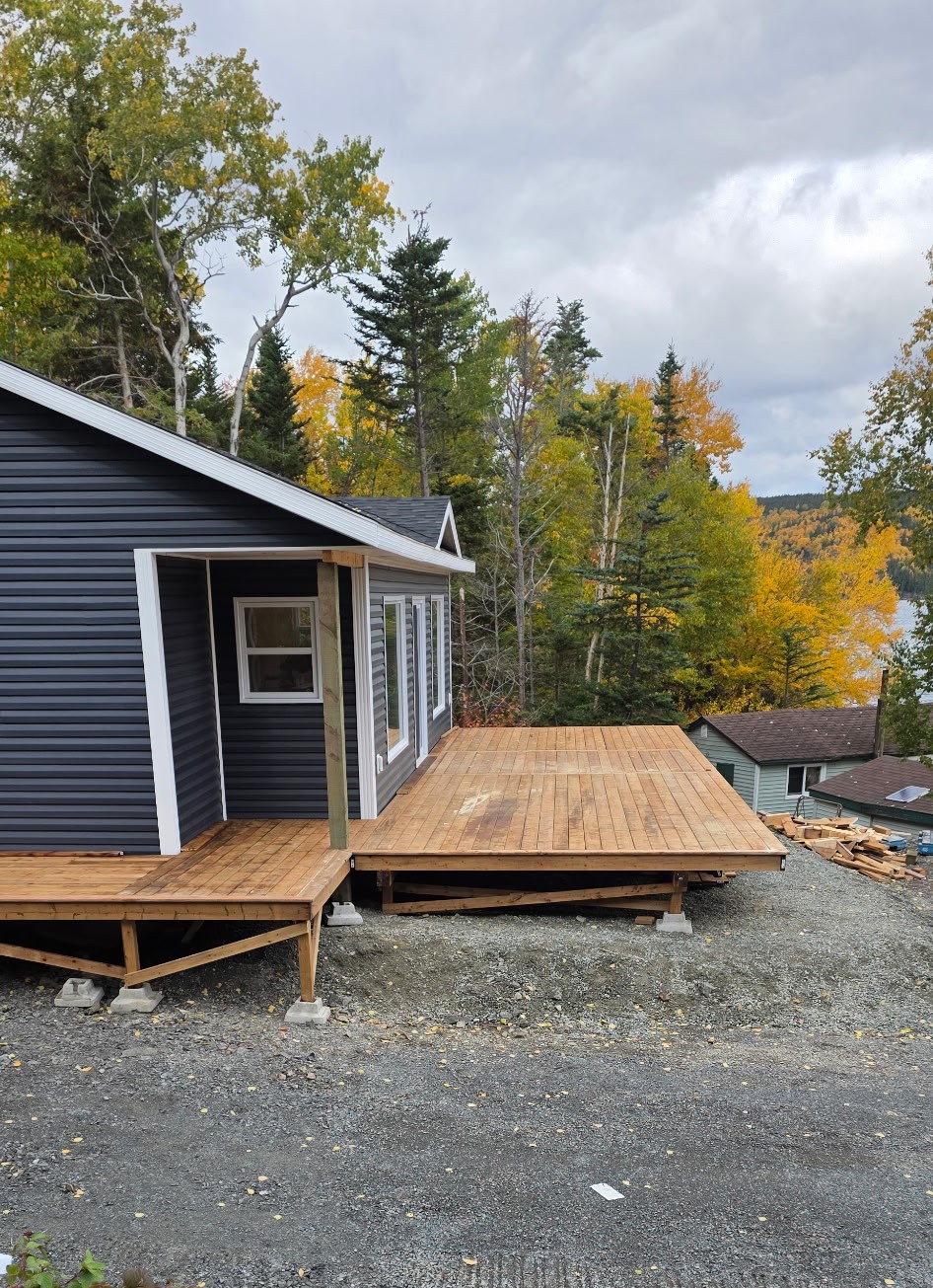 Large custom wood deck wrapping around a dark-sided home